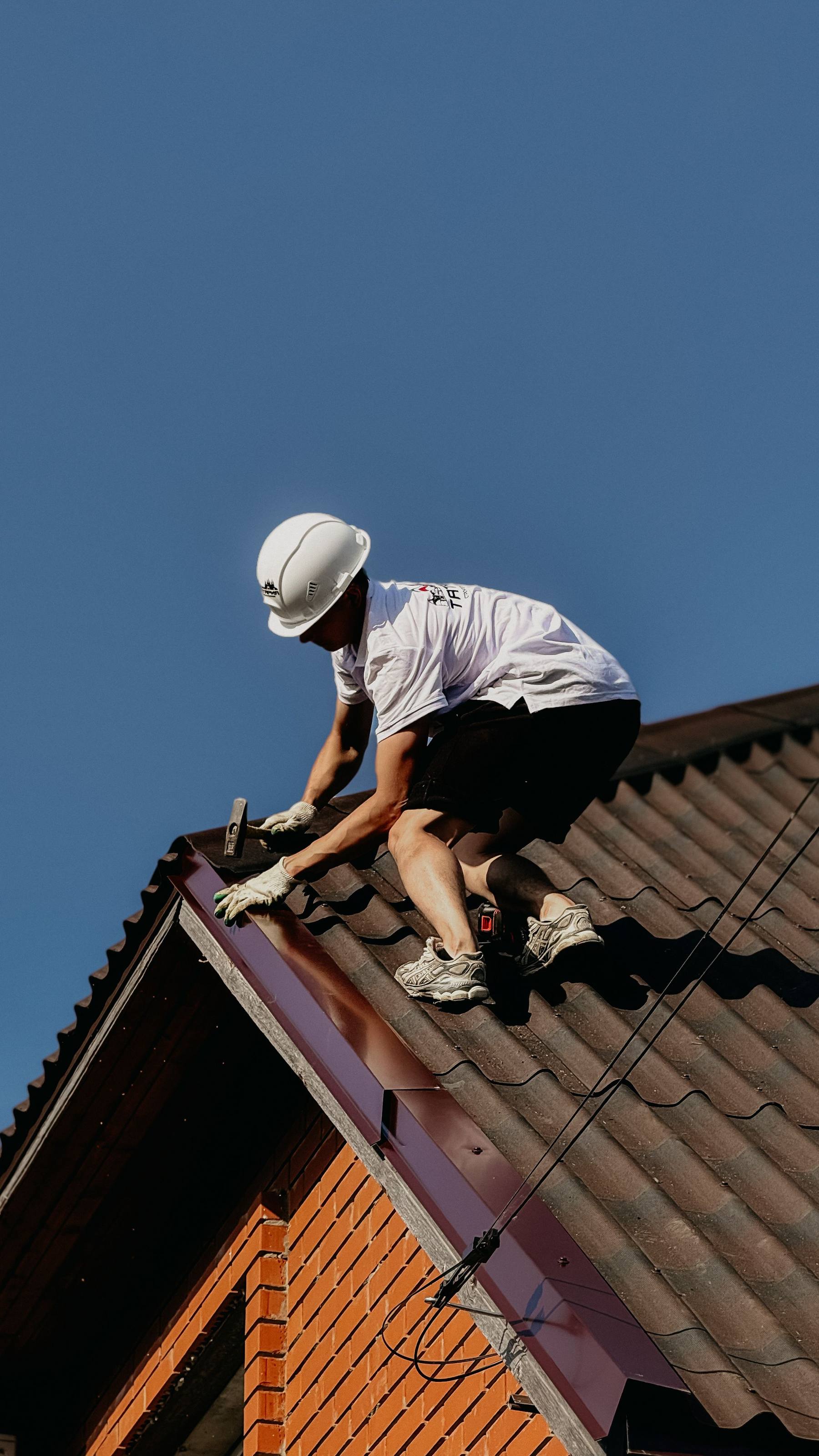 Dachdecker arbeitet am First eines neu eingedeckten Daches